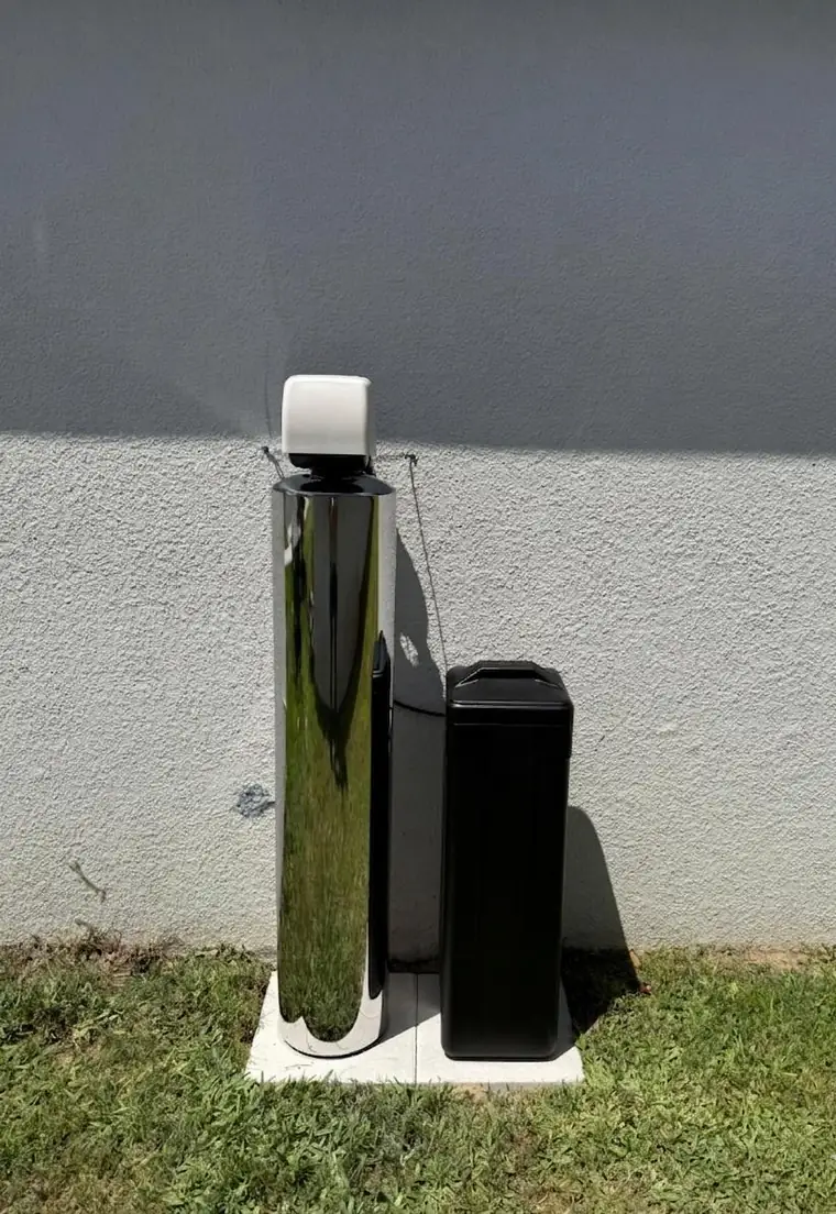 Stainless steel whole-home water filtration system installed outside a house